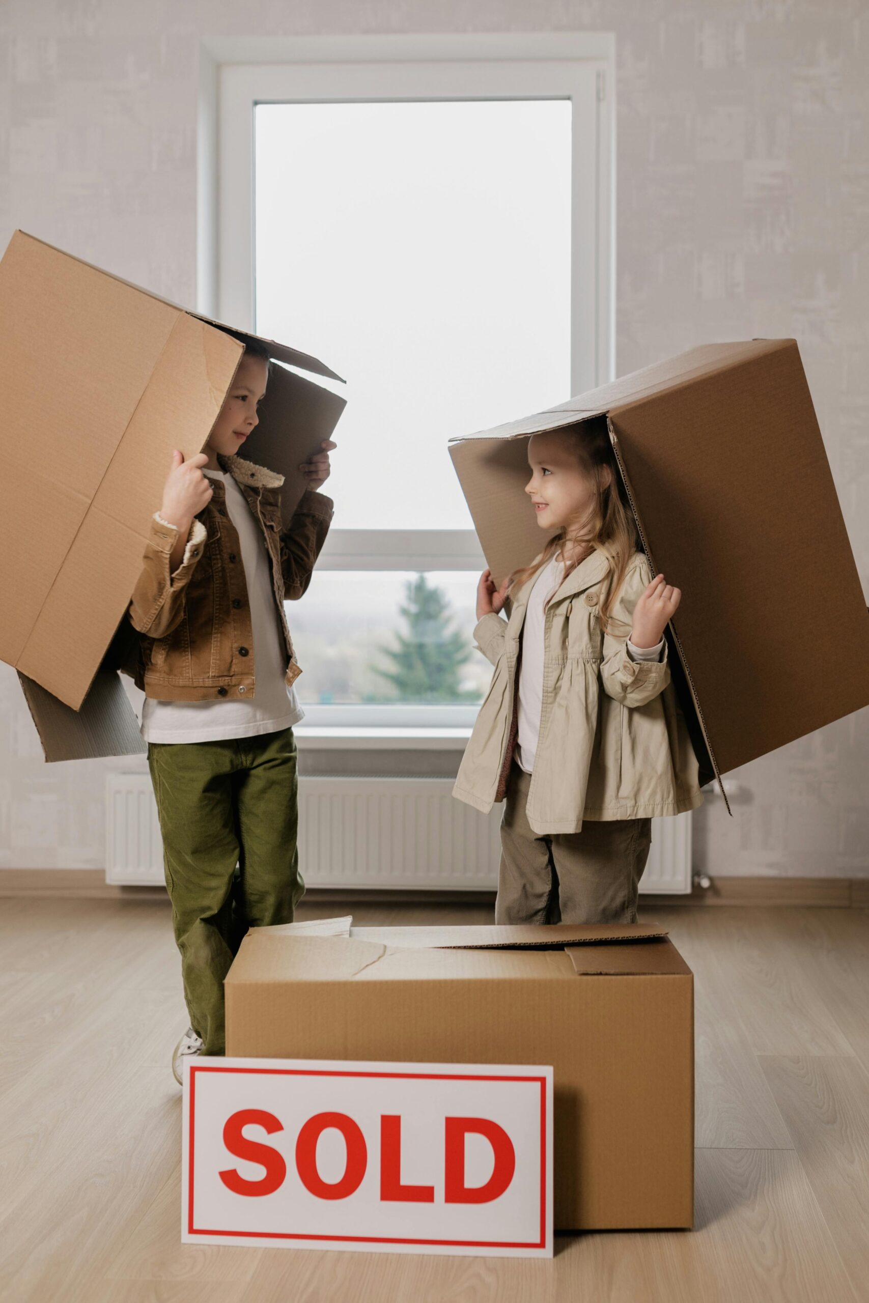 Home Two girls play creatively with cardboard boxes in a cozy room.